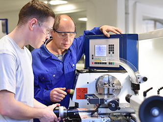 Photo of two workers looking at a machine