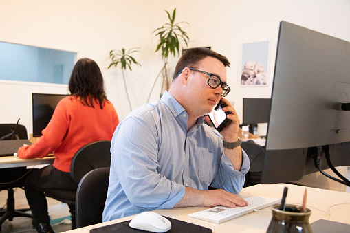 young adult at work talking to a customer on the phone